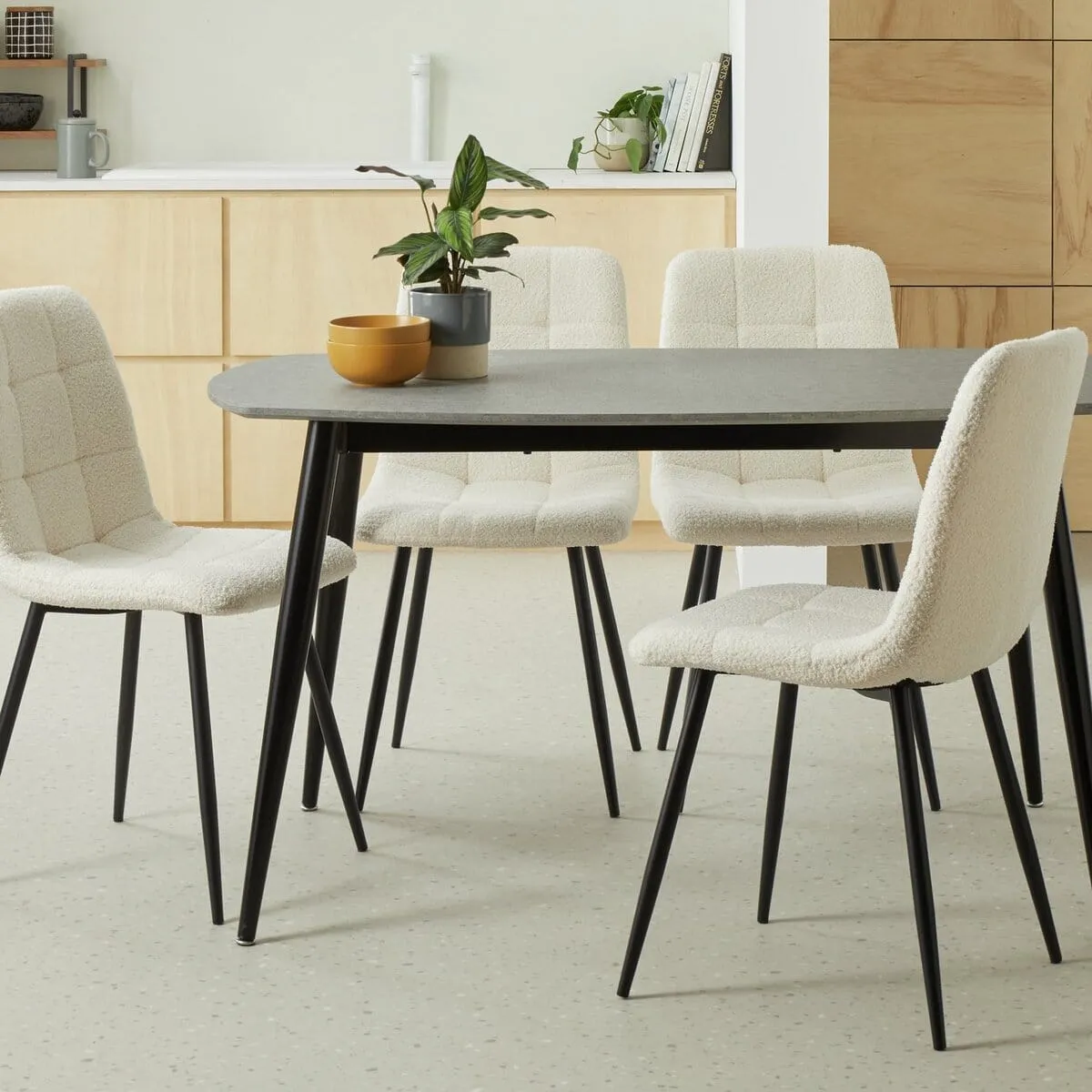 Grey top dining table with black legs and 4 white boucle chairs