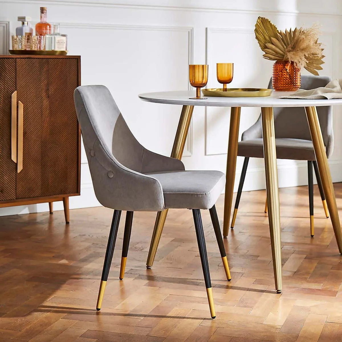 Grey velvet dining chair with black and gold legs