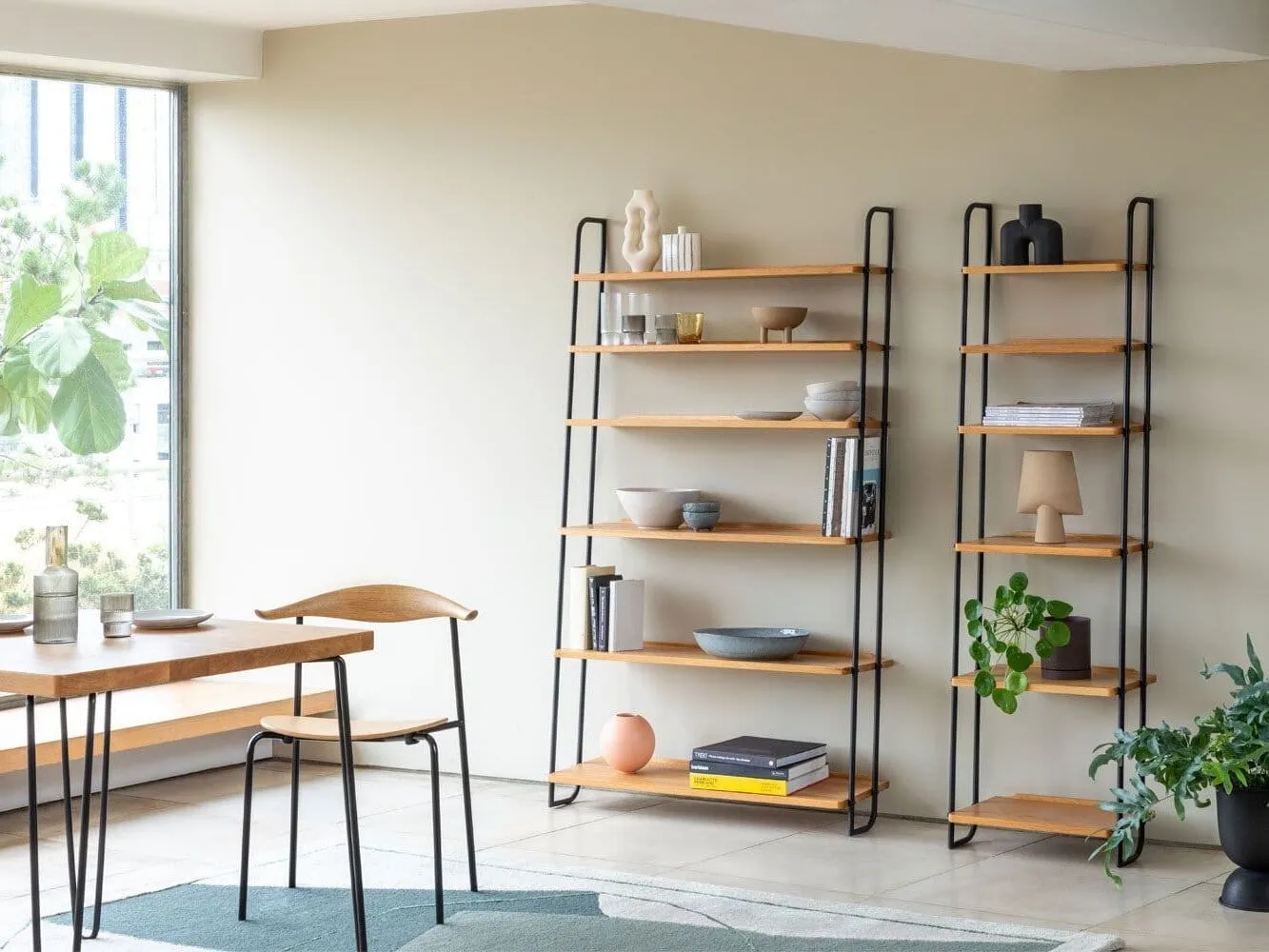 Pair of leaning oak shelving units with black metal frames