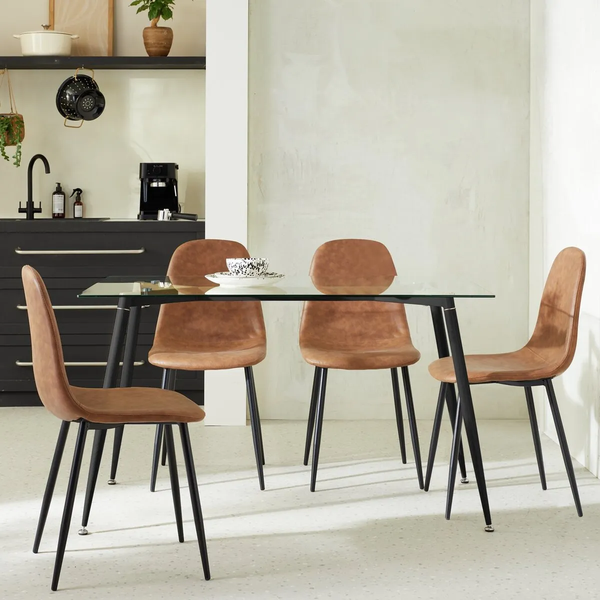 Glass topped dining table with black legs and 4 faux leather dining chairs