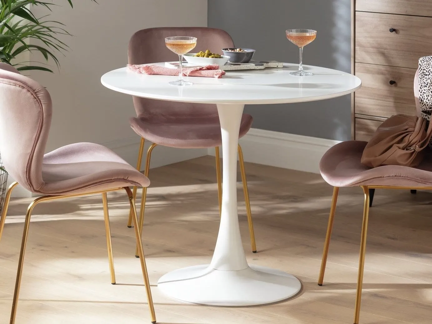 Round white dining table with a slender stem base