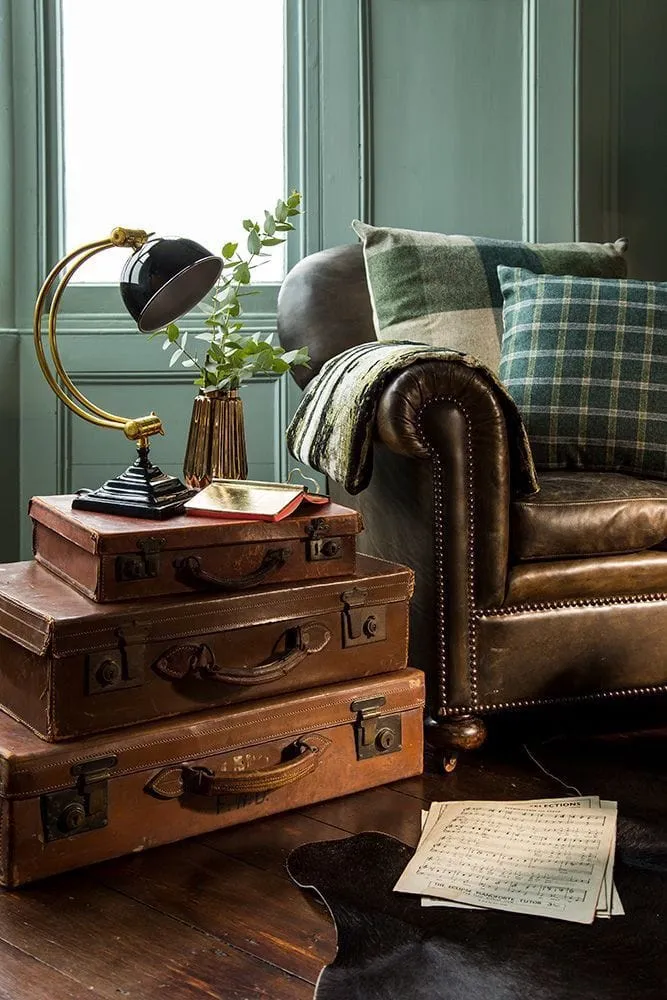 A stack of 3 vintage suitcases used as a side table