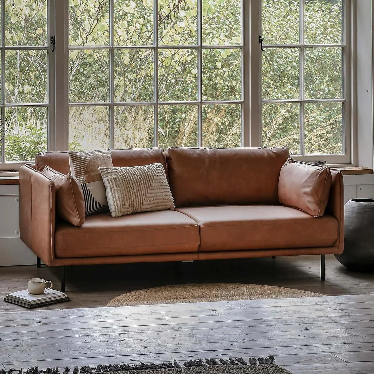 Leather sofa with slender arms and bolster cushions - mounted on slim black metal legs