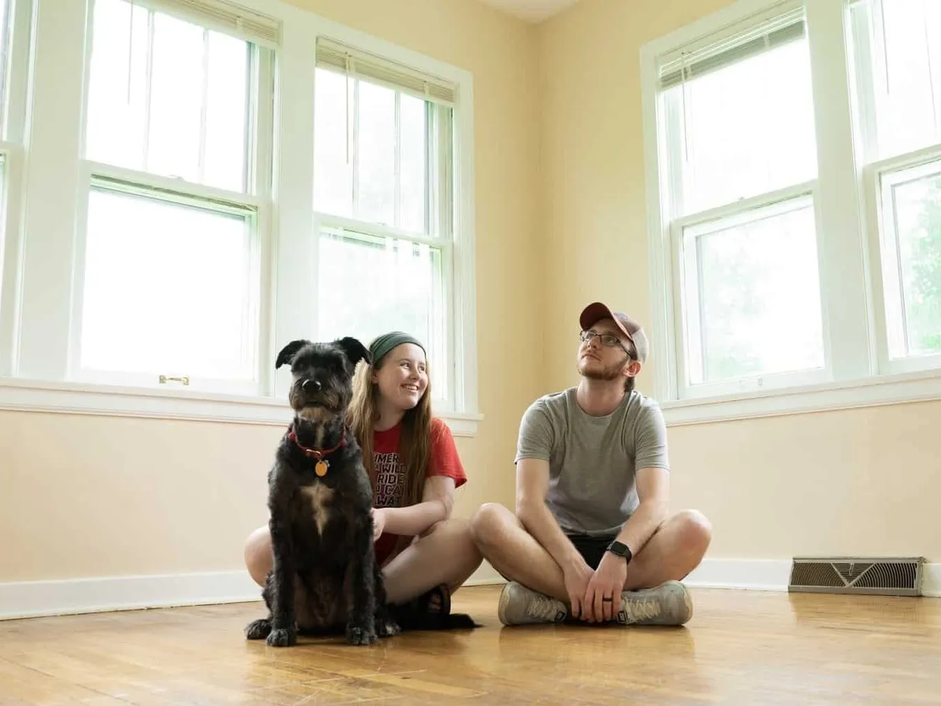 Couple and a dog sat on a polished wooden floor
