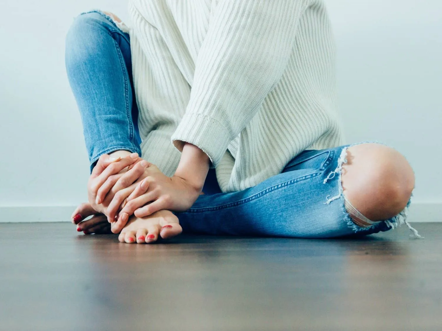 Girl in torn jeans sat on a hard floor